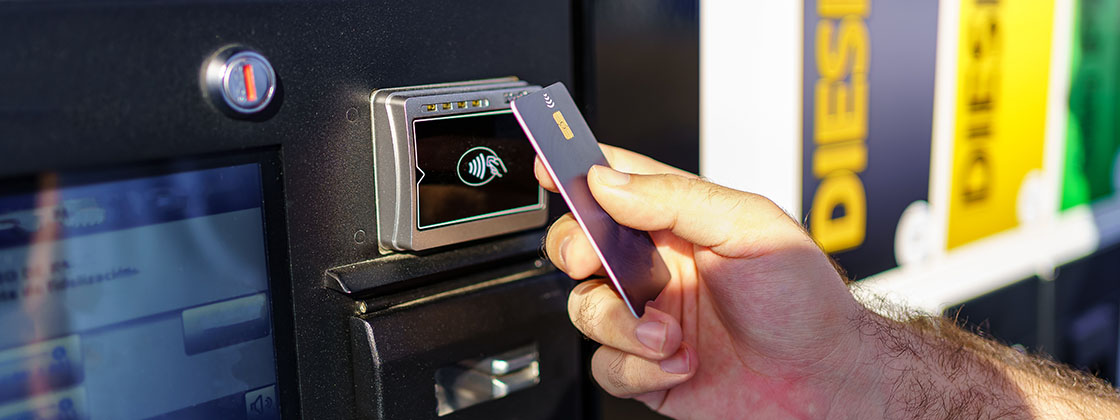 A close up of a fleet employee tapping a fuel card at a gas station to pay for a vehicle fuel refill.