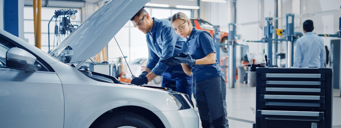 Two auto workers under vehicle hood