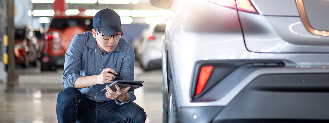 auto worker kneeling next to tire