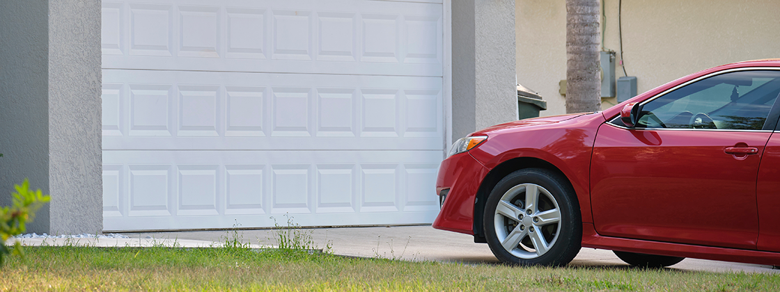 A red company car parked in front of a residential garage door.