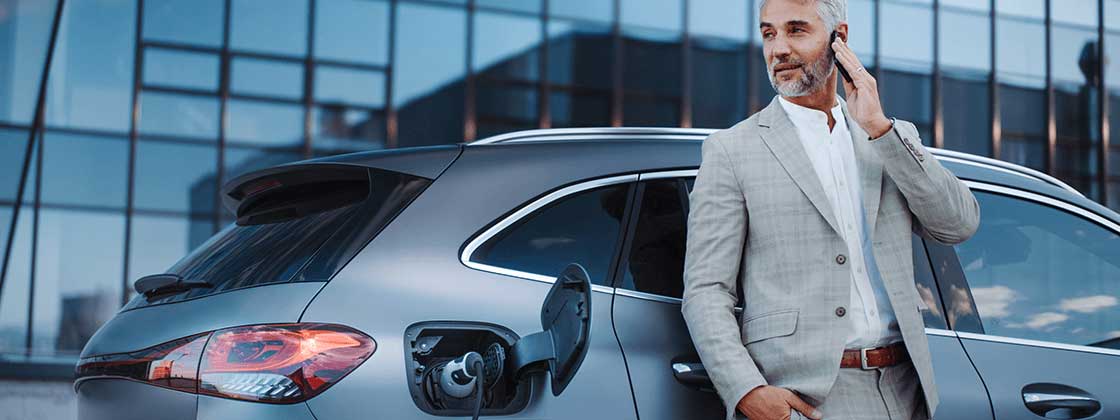 Man on phone standing next to electric vehicle