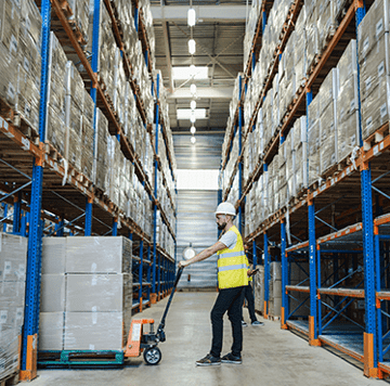 Man in warehouse using a piece of equipment to move materials