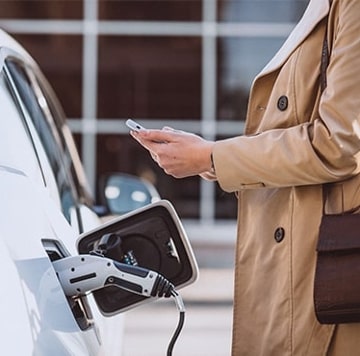 Woman checking phone next to EV